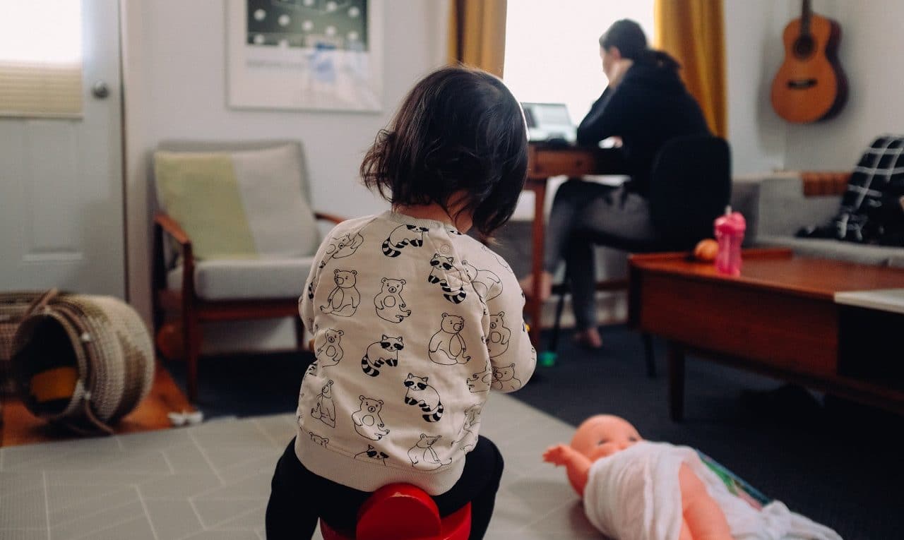 mom working from home with toddler playing next to her